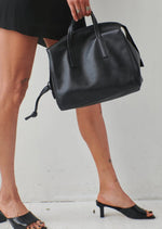 Harmin Your Handle Bag in Black. Perfectly proportioned, YOUR HANDLE is a daily companion that exudes modern glamour. Features include interior flaps for added security and can be worn handheld, on the forearm, or add adjustable strap for hands-free ease.   The adjustable strap is included in the price.  Dimensions: 12 ⅞ wide (18 ⅞” with gussets extended), 8 ¼” long, 6 ¼” deep  Made in Italy Luxury Leather Fully Washable Lining Lightweight Construction Utilitarian Zipper